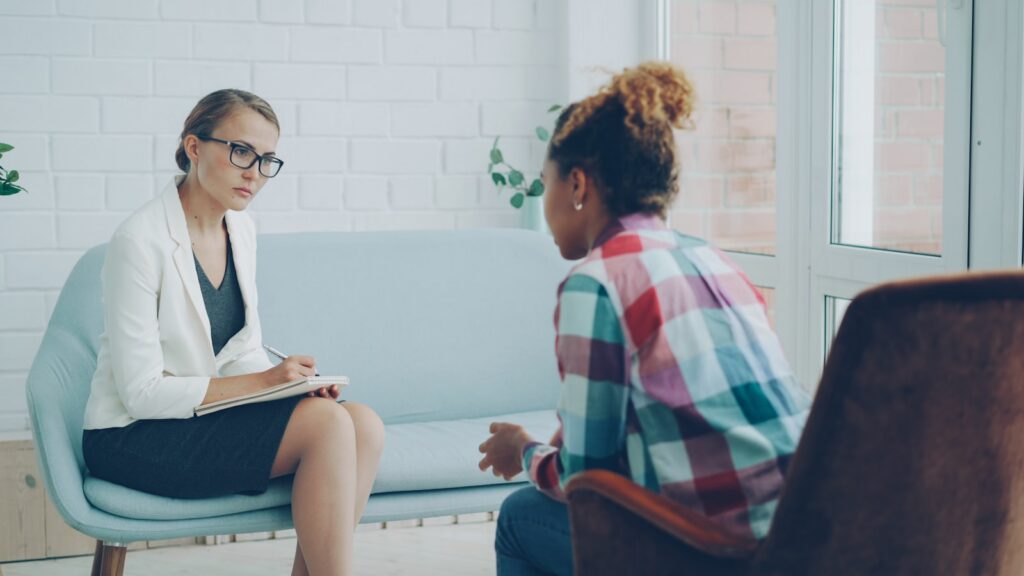 Therapist in a counseling session taking notes with a client